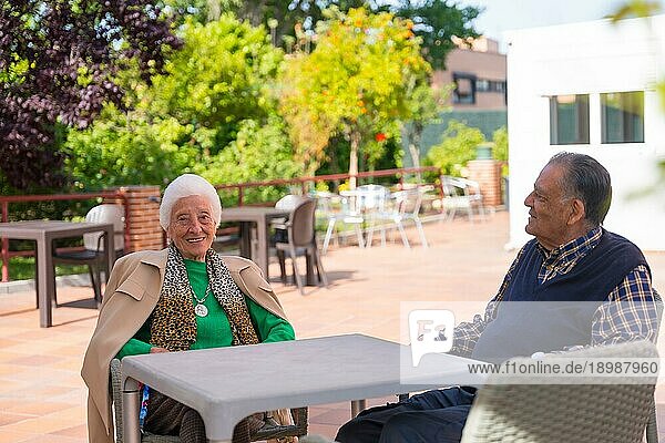 Zwei sehr fröhliche ältere Menschen im Garten eines Pflegeheims  die sich an einem sonnigen Sommertag ausruhen