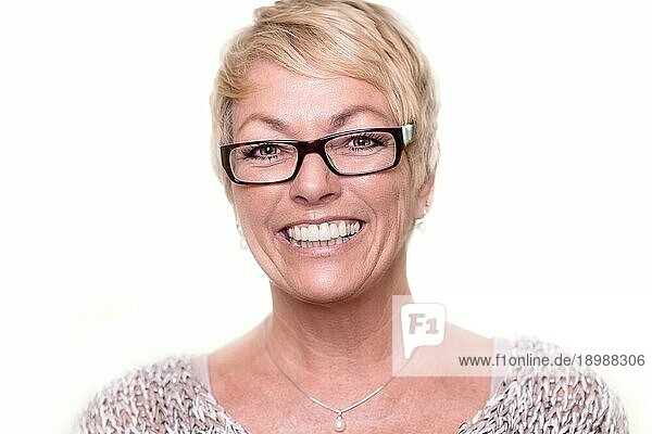 Kopf Schulter Porträt einer glücklichen  attraktiven blonden Frau mittleren Alters  die eine Brille trägt und mit einem schönen  lebhaften Lächeln in die Kamera schaut