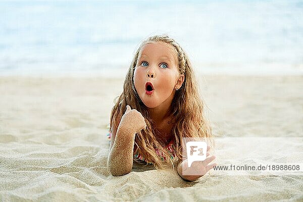 Überrascht niedlichen kleinen blonden Mädchen entspannen am Strand im Sommerurlaub. Lustige Kinder  wow Emotionen Konzept