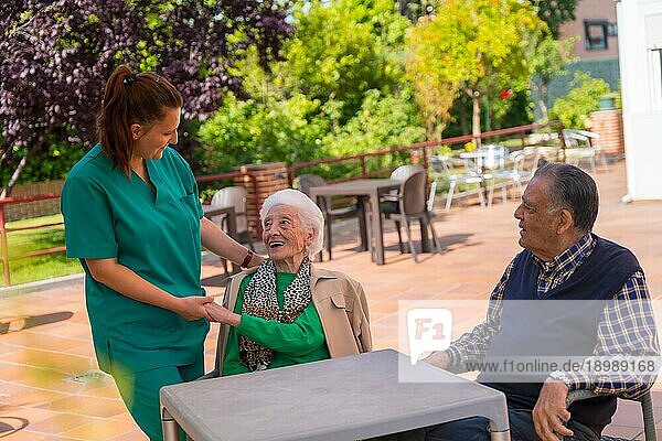 Zwei ältere Menschen mit der Krankenschwester im Garten eines Pflegeheims oder Seniorenheims  alter Mann und alte Frau