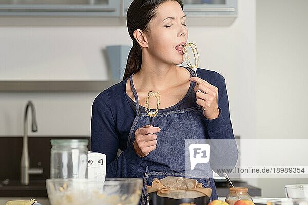 Close up Pretty Woman Backen in der Küche  Verkostung von Lebensmitteln auf Handmixer  während der Blick in die Kamera