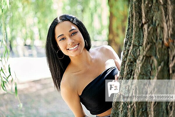 Hübsche lächelnde afroamerikanische Frau posiert im Park. Entspannen  Freizeit  weibliche Schönheit Konzept