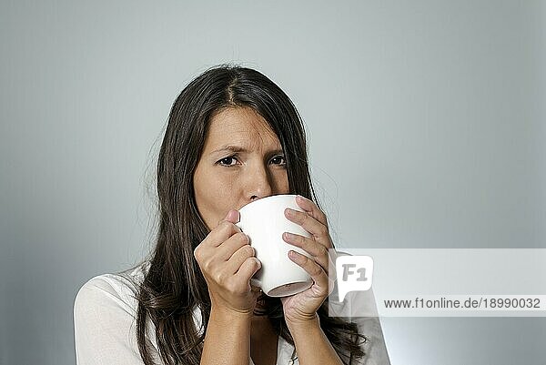 Frau trinkt Kaffee aus einem weißen Becher