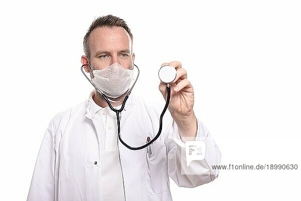 Lächelnder  unrasierter männlicher Arzt  der die Scheibe eines Stethoskops in der Hand hält und bereit ist  eine Untersuchung durchzuführen  während er in die Kamera blickt  vor weißem Hintergrund