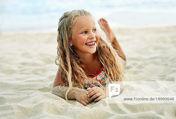 Adorable kleine blonde Mädchen entspannen am Sandstrand genießen Meer. Lächelnd hübsches Kind posiert am Strand. Sommerurlaub  glückliche Kindheit und Emotionen Konzept