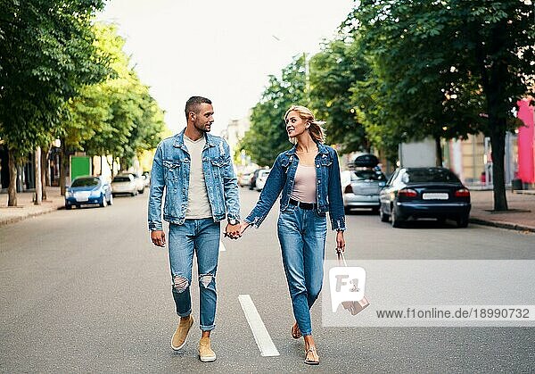 Schönes junges Paar hält sich an den Händen und lächelt beim Spaziergang im Freien. Liebe  Dating Konzept