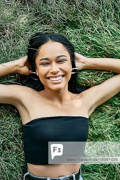 Oben Ansicht Porträt der hübschen glücklichen afroamerikanischen Frau entspannt auf Gras im Park. Rest  weibliche Schönheit Konzept