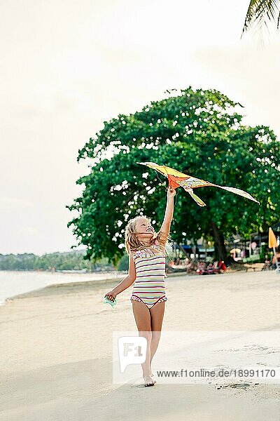 Happy hübsches Kind Mädchen mit einem Drachen läuft auf tropischen Strand im Sommer. Meer Spaß  Kindheit Konzept