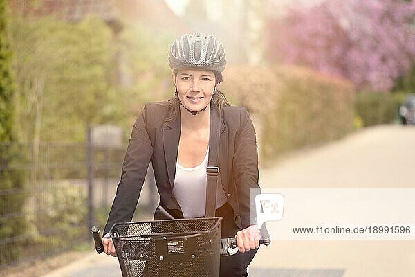Glückliche junge Geschäftsfrau Radfahren auf der Straße mit Kopfbedeckung Going to her Office  Blick in die Kamera