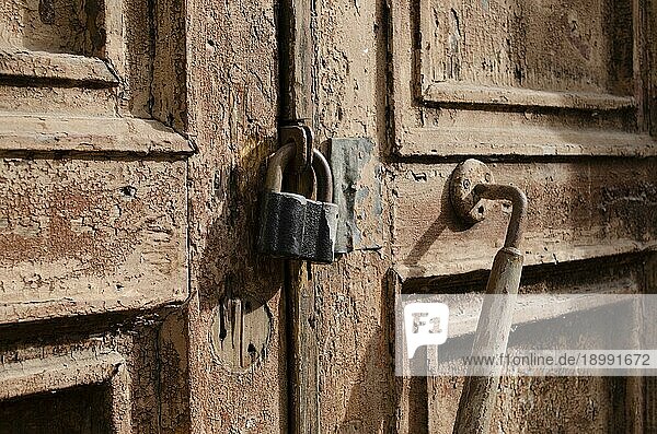 Das Schloss der alten Holztür in Großaufnahme. Rost auf dem Metallschloss. Abblätternde braune Farbe an der alten Tür. Alte Textur