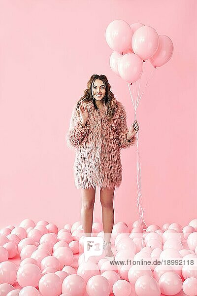 In voller Länge Porträt der glücklichen Glamour Frau mit rosa Luftballons auf rosa Pastell Hintergrund. Party  kreativ  Feier Konzept. Menschen Emotionen