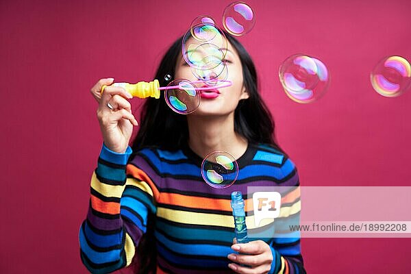 Glückliche schöne Frau bläst Seifenblasen isoliert über rosa Hintergrund