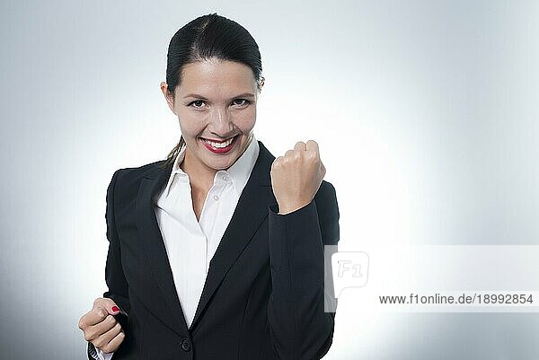 Schöne  jubelnde junge Geschäftsfrau  die mit einem strahlenden  begeisterten Lächeln im Gesicht einen Erfolg feiert  mit Kopiervorlage