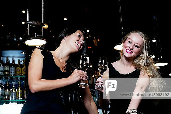 Zwei schöne junge Frauen teilen ihre Freundschaft und feiern mit Champagner in einem schicken Nachtclub