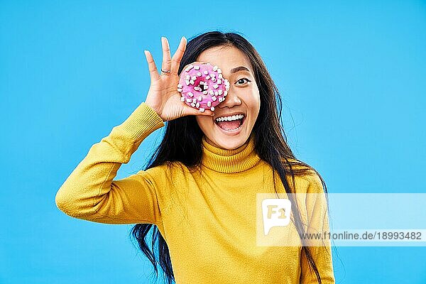 Attraktive Frau hat Spaß mit Donuts. Mädchen zeigt Donuts vor ihren Augen auf blauem Hintergrund. Leckeres Essen  Diätkonzept