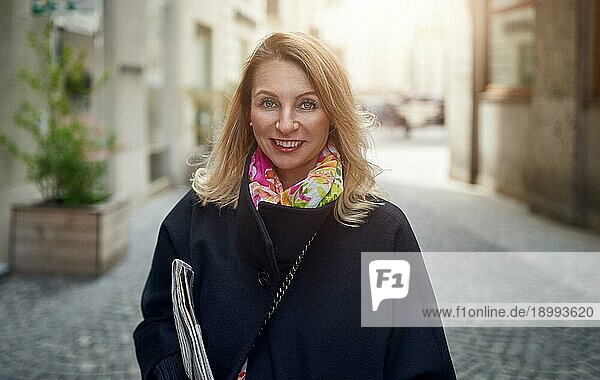 Outdoorporträt von blonde reife lächelnde Frau auf der Straße stehen