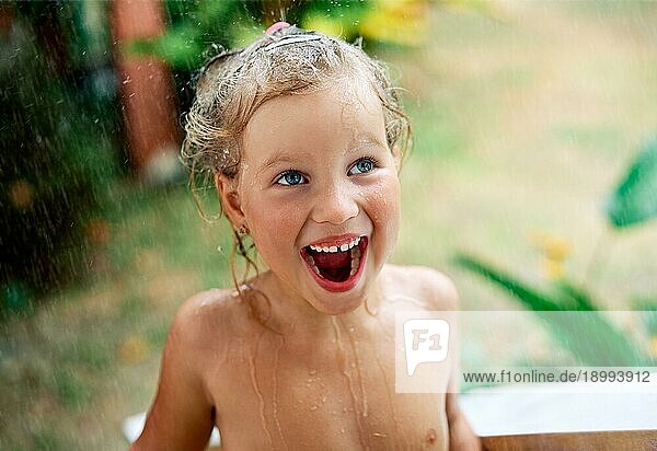 Close up Porträt der glücklichen niedlichen kleinen Mädchen genießen Sommer regen. Tropfen fallen auf ihr Gesicht  Kind lächelnd. Kindheit  Emotionen und Urlaub Konzept
