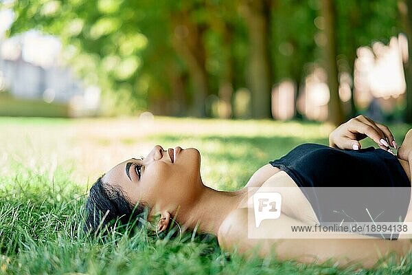 Hübsche afroamerikanische Frau entspannt sich auf Gras im Park. Ruhe  weibliche Schönheit Konzept
