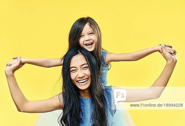 Glückliche Mutter und ihr Kind Tochter haben Spaß zusammen auf gelbem Hintergrund. Familie  umarmen Konzept