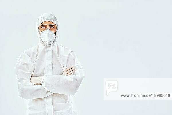 Selbstbewusster Arzt mit verschränkten Armen im medizinischen Schutzanzug mit Kopierraum auf weißem Hintergrund