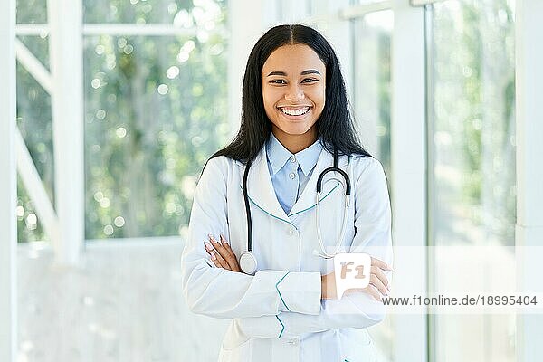 Lächelnde afroamerikanische Ärztin mit verschränkten Armen im Krankenhaus. Medizin  Beruf und Gesundheitswesen Konzept