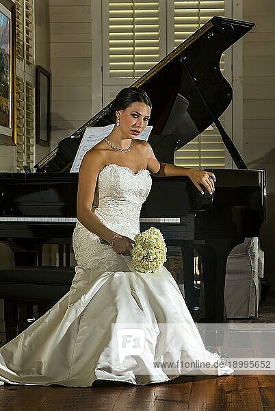 Eine moderne Braut posiert drinnen mit einem Flügel