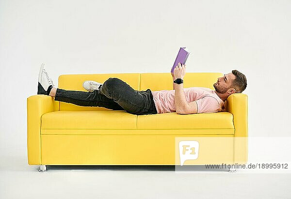 Mann entspannt sich auf dem Sofa und liest ein Buch. Ruhe  Hobby Konzept