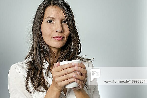 Frau trinkt Kaffee aus einem weißen Becher