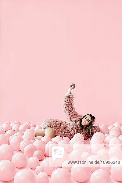 Modeporträt von lächelnden hübsche Frau in vielen rosa Luftballons auf rosa Pastell Hintergrund mit Kopie Raum liegen. Entspannen  Party  Menschen Konzept