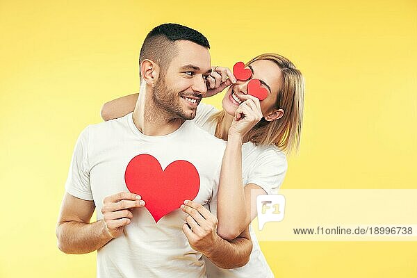 Glückliches Paar in der Liebe haben Spaß mit Papier Herzen auf gelbem Hintergrund. Beziehung und romantisches Konzept