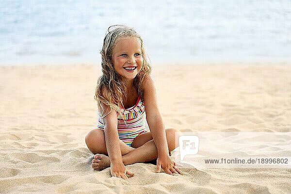 Adorable kleines Mädchen entspannen am Sandstrand im Sommerurlaub. Glückliche Kindheit Konzept