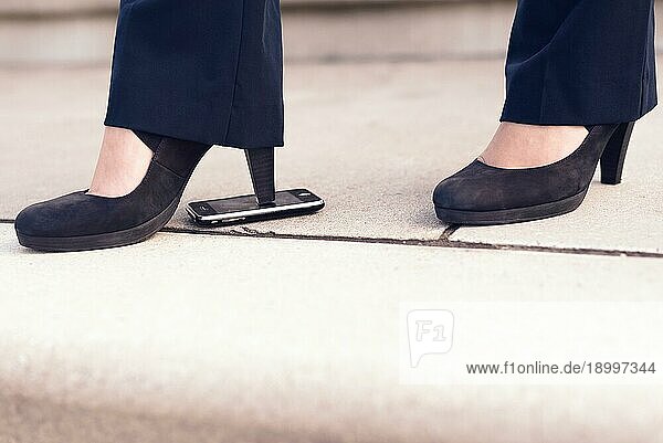 Frau Füße in schwarzen Schuhen mit Absätzen Schritt auf Handy auf dem Boden