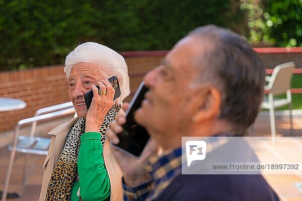 Zwei ältere Menschen im Garten eines Altenheims  die miteinander telefonieren  Technologien für ältere Menschen