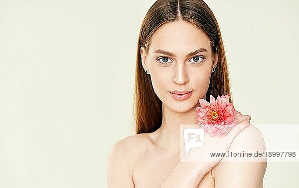 Close up Porträt der schönen jungen Frau hält Blume auf Studio Hintergrund mit Kopie Raum. Weibliche Schönheit  Spa  saubere Haut Konzept