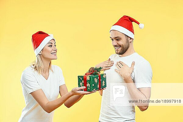 Junge Frau geben Weihnachten Geschenkbox an Mann vorgelbem Hintergrund. Geschenk  Urlaub  Feier Konzept