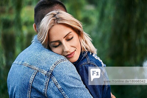 Junge schöne Frau umarmt ihren Freund mit Liebe im Freien. Kaukasisches Paar im Park. Zärtlichkeit  Vertrauen  glückliche Beziehung Konzept