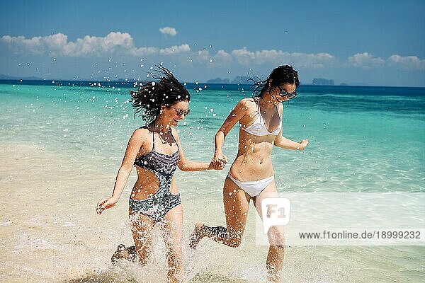 Zwei junge Frauen  die Spaß haben  lachen und laufen auf dem tropischen Strand während des Sommerurlaubs. Freiheit  Reiseziel  entspannen Konzept