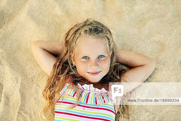 Hübsches kleines blondes Mädchen Porträt auf Sandstrand während der Sommerferien liegen. Meer entspannen  glückliche Kindheit Konzept