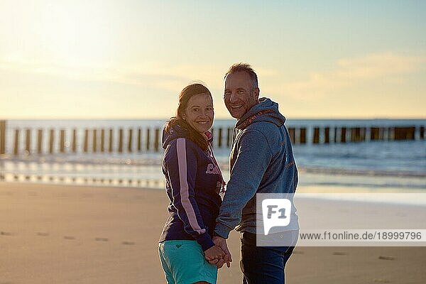 Glückliches  frisch entjungfertes Paar am Strand im Sommer lächelt in die Kamera
