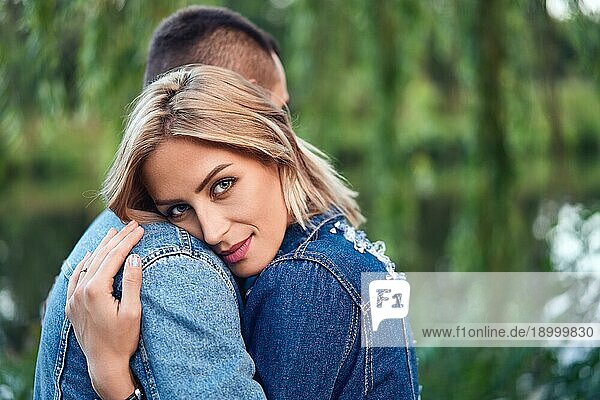 Junge schöne Frau umarmt ihren Freund mit Liebe im Freien. Kaukasisches Paar im Park. Zärtlichkeit  Vertrauen  glückliche Beziehung Konzept