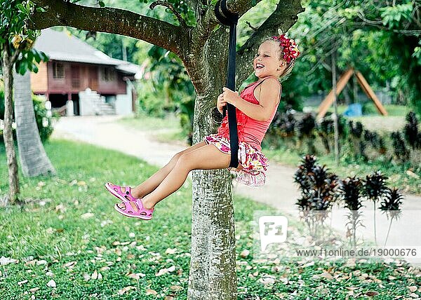 Happy lachendes Kind Mädchen auf Schaukel im Freien. Sommer Aktivität für Kinder. Kindheit Konzept