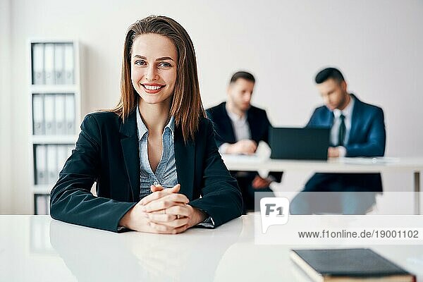 Happy lächelnd BusinessFrau Porträt sitzt im Büro mit ihrem Businessteam auf dem Hintergrund. Führung und Erfolg Konzept