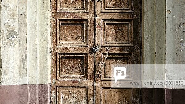 Verlassene alte Tür mit Schloss. Rost auf dem Metallschloss. Abblätternde braune Farbe an der alten Tür