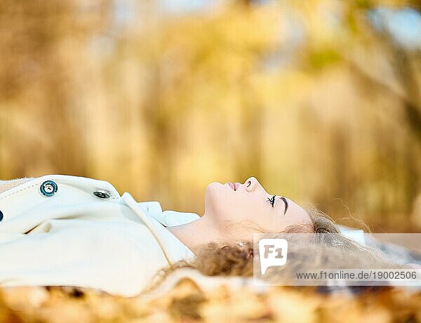 Herbstporträt von glücklichen lächelnde junge Frau entspannt liegend im Herbst gelbe Blätter mit Kopie Raum. Happy Herbst  Ruhe  weibliche Schönheit Konzept