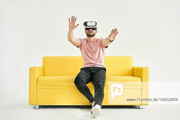 Junger Mann mit Virtual Reality Headset spielt Videospiele und versucht  etwas mit den Händen zu berühren