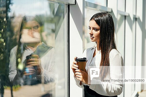 Porträt eines eleganten Geschäftsmannes mit einer Tasse Kaffee in der Hand während der Pause in einem modernen kreativen Büro mit Kopierraum. Entspannen  Erfolg Konzept