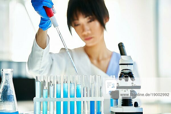 Asiatischer Wissenschaftler  der in einem großen modernen Labor arbeitet und forscht. Medizin  Mikrobiologie  Biotechnologie Konzept