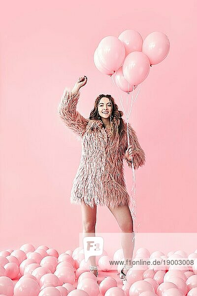 In voller Länge Porträt der glücklichen Glamour Frau mit rosa Luftballons auf rosa Pastell Hintergrund. Party  kreativ  Feier Konzept. Menschen Emotionen