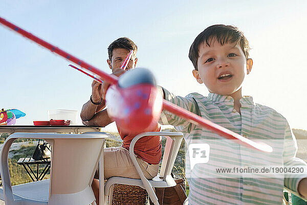 Boy playing with toy airplane on sunny day