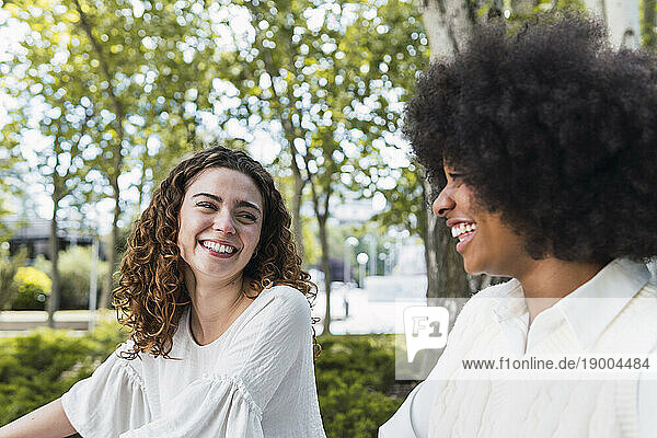 Smiling curly haired woman spending time with friend